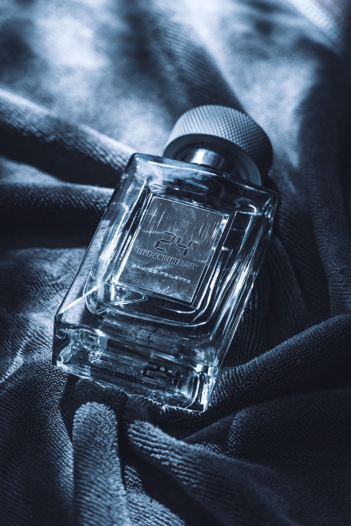 Flacon de parfum sur tissu sombre